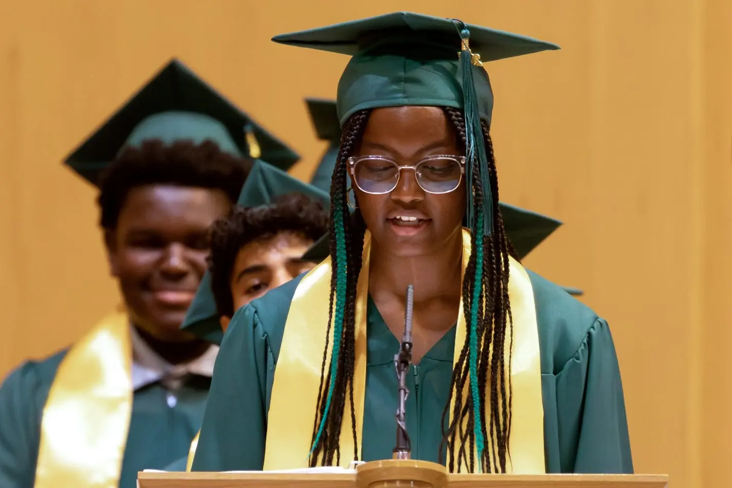 Nativity Preparatory Academy graduates speaking at a lectern