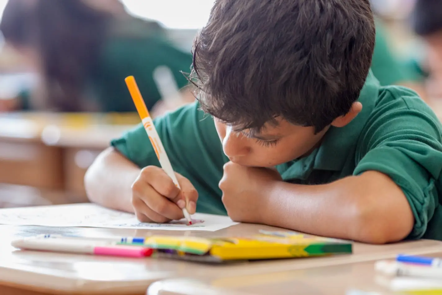 A Nativity student at their desk working on art